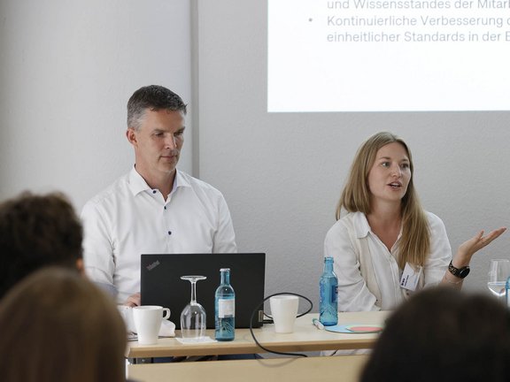 Zwei Mitarbeiter von Holtmann+ erklären etwas im Rahmen eines Vortrags.